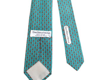 May include: A turquoise silk tie with a repeating pattern of small red and white squares. The tie has a label that reads "Gian Marco Venturi 100% Silk Made in Italy".