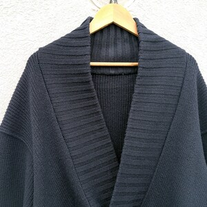 Puede incluir: Un c&aacute;rdigan azul marino oscuro con cuello chal. El su&eacute;ter est&aacute; hecho de una tela de punto acanalado y cuelga de una percha de madera. La prenda tiene un ajuste relajado y un dise&ntilde;o cl&aacute;sico.