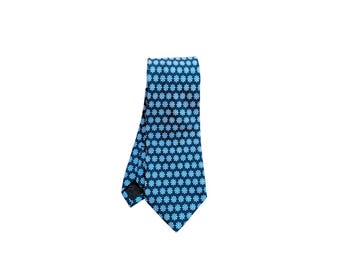 Puede incluir: Una corbata azul marino con un patrón repetido de diseños florales azul claro. La corbata está hecha de una tela suave y se muestra sobre un fondo blanco. Un accesorio clásico para vestimenta formal o de negocios.