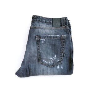 Könnte beinhalten: Eine weiße Keramik-Tasse mit schwarzem Henkel und dem Text "But First, Coffee" in fetter, schwarzer Schrift. Die Tasse steht auf einer Holzoberfläche. Die Tasse ist etwa 10 cm hoch.