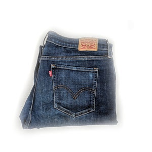 Könnte beinhalten: Eine blaue Jeanshose, die in der Hälfte gefaltet ist, mit einem roten und weißen Levi's-Etikett auf der Gesäßtasche.