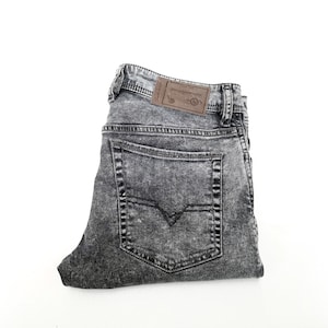 Könnte beinhalten: Eine graue Jeans mit Säurewäsche und einem braunen Lederpatch auf der Gesäßtasche.