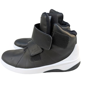 Könnte beinhalten: Schwarze High-Top-Sneaker mit weißen Sohlen. Die Sneaker haben einen Klettverschluss und ein Nike-Logo. Sie verfügen über einen gepolsterten Kragen und eine Zunge. Geeignet für sportliche Aktivitäten.