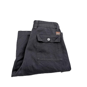 Op de afbeelding: Een zwarte cargo broek met een enkele knoopzak op de achterkant.