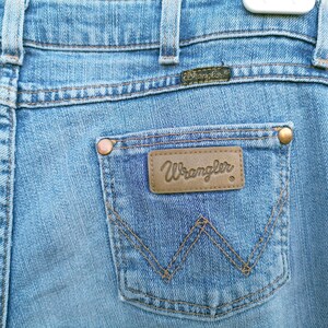 May include: A pair of blue denim jeans with a brown leather patch that says "Wrangler" on the back pocket.