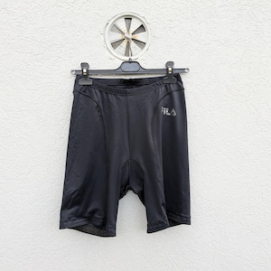 Puede incluir: Pantalones cortos deportivos negros con un corte ajustado y tejido el&aacute;stico liso. La prenda incluye una cintura el&aacute;stica negra y el logotipo de la marca FILA impreso en un tono gris oscuro en la parte superior del muslo izquierdo.