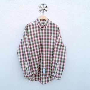 May include: A long-sleeved button-down shirt in a plaid pattern of red, green, and white. The shirt is hanging on a wooden hanger against a white wall. The shirt has a button-down collar and cuffs.