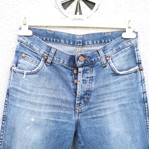 May include: A pair of light blue denim jeans with a faded wash and a classic five-pocket style. The jeans have a button fly and a straight leg.