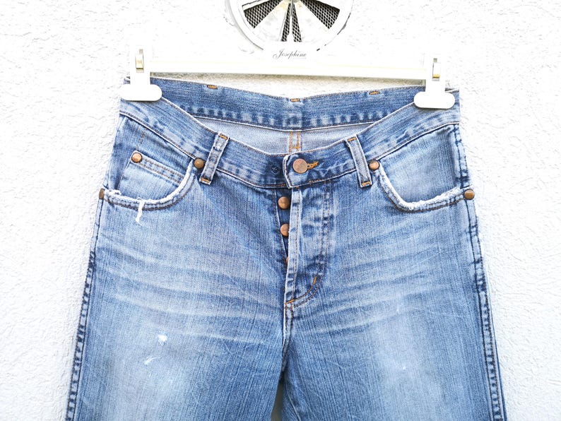 May include: A pair of light blue denim jeans with a faded wash and a classic five-pocket style. The jeans have a button fly and a straight leg.
