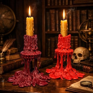 May include: Two lit candles in decorative holders. The candles are yellow, and the holders are red and burgundy, with a dripping wax design. The background includes a bookshelf, a globe, a skull, and books, creating a gothic or Halloween theme.