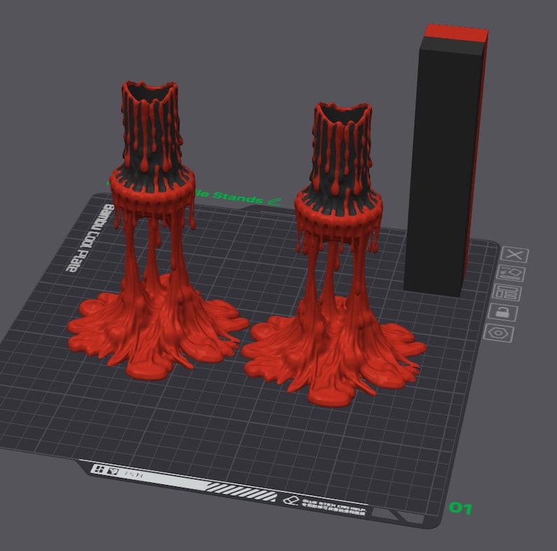 May include: Two black and red candle holders with a unique design. The candle holders have a textured, dripped wax appearance. A black and red rectangular object is also present.