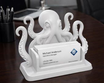May include: A white octopus-shaped business card holder. The holder features a detailed octopus design with tentacles and a slot to hold business cards. The business cards have the name "Michael Anderson" and contact information printed on them.