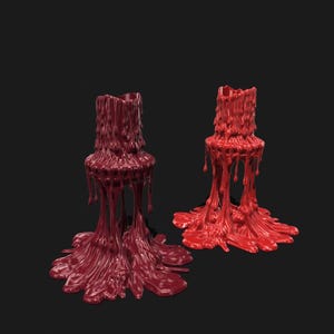 May include: Two candle holders with a melted wax design. One is a deep burgundy color, and the other is a bright red. The wax appears to be dripping down the sides and pooling at the base, creating a unique and artistic look.
