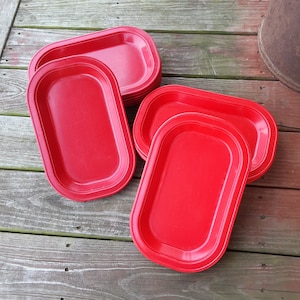 May include: A set of six red plastic oval serving trays. The trays are stacked on top of each other.