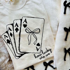 Camiseta gráfica "How Lucky Are We", camiseta gráfica fofa, camiseta com fita, bordado, camiseta gráfica com fita, camiseta gráfica da moda