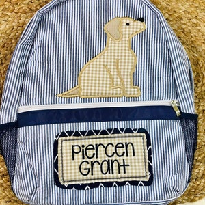 May include: Blue and white striped backpack with a brown and white dog applique and a name tag that reads "Piercen Grant".