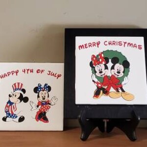 May include: Set of six ceramic tiles featuring Mickey and Minnie Mouse celebrating different holidays. The tiles are white with colorful illustrations and text. The holidays include Valentine's Day, Easter, 4th of July, Halloween, Thanksgiving, and Christmas.