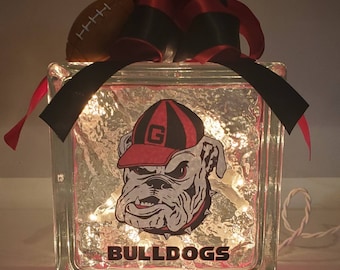 May include: A glass block with a light inside, decorated with a red and black ribbon, a football, and a bulldog mascot with the word "BULLDOGS" printed below.