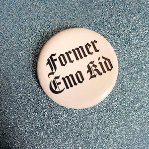 May include: A white button with the text "Former Emo Kid" in black gothic font. The button is round and set against a sparkly, light blue background.