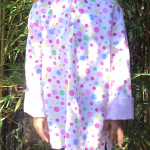 May include: A white long-sleeved shirt with a pink, blue, green, and yellow polka dot pattern. The shirt has a button-up front and a relaxed fit.