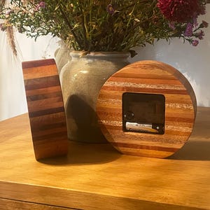 May include: Two round wooden clocks with a striped design. The clock on the right has a battery compartment visible.
