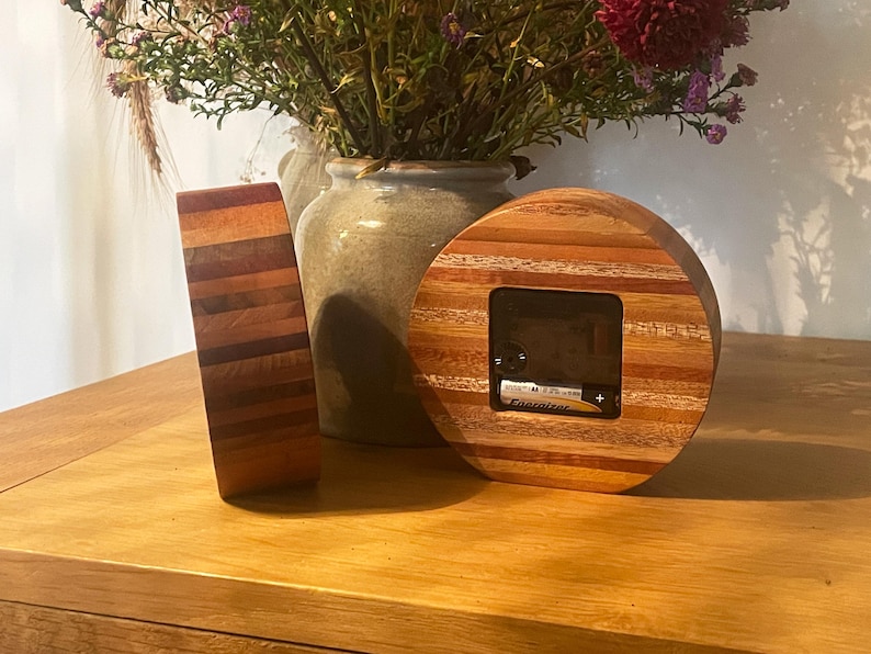 May include: Two round wooden clocks with a striped design. The clock on the right has a battery compartment visible.