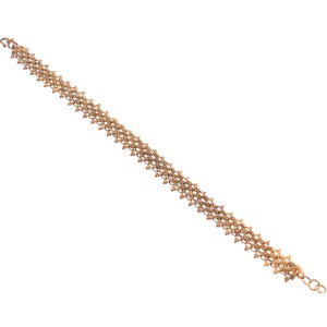 May include: A gold chain bracelet with a delicate, intricate design. The chain is made up of small, linked squares.