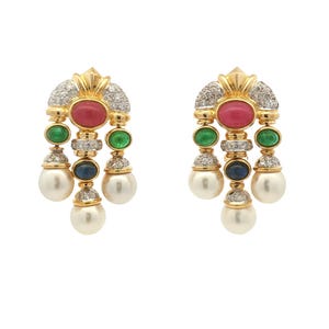 May include: A pair of gold-toned earrings with a cluster design. Each earring features a red oval stone, two green stones, a blue stone, and a dangling white pearl. The top section is encrusted with small clear stones.