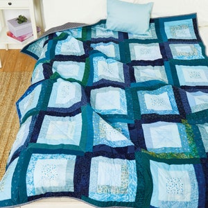 May include: A blue and green patchwork quilt with a square pattern. The quilt is made of different shades of blue and green fabric, and it has a simple, modern design.