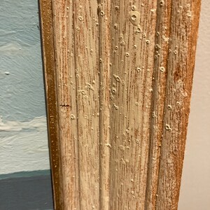 May include: Close-up of a wood frame with a white painted finish and a gold trim. The frame has a distressed look with small holes and imperfections in the paint.