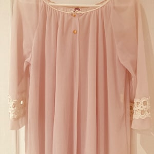 May include: A pale pink sheer blouse with a button closure and lace trim on the sleeves.