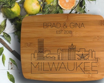 Może przedstawiać: Spersonalizowana bambusowa deska do krojenia z czarno-białym zarysowaniem panoramy Milwaukee. Deska jest grawerowana napisem "Brad & Gina Est 2018" i słowem "Milwaukee".