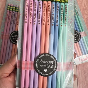 May include: A set of ten pastel-colored pencils with green metal ferrules and pink erasers, packaged in clear plastic. Each pencil is imprinted with the name GIANNA GILBERT and a star. A black circular sticker reads HANDMADE WITH LOVE.
