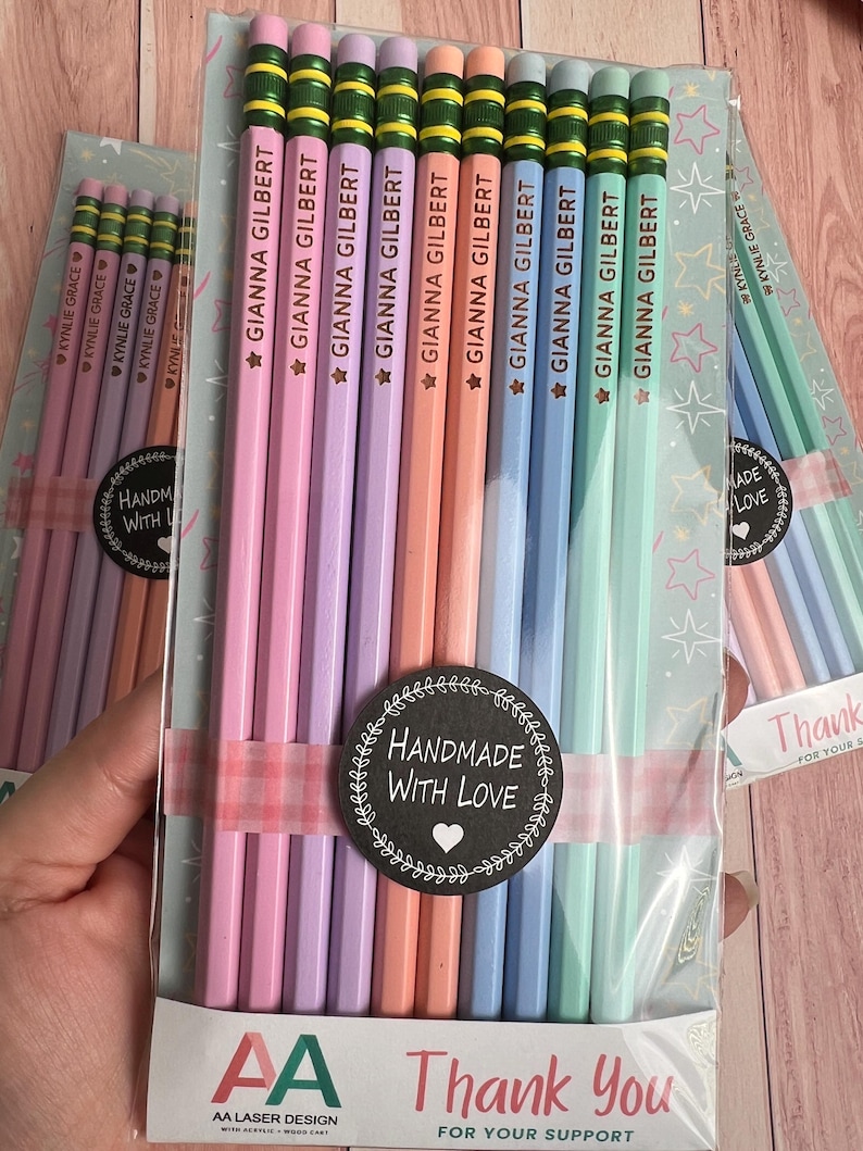 May include: A set of ten pastel-colored pencils with green metal ferrules and pink erasers, packaged in clear plastic. Each pencil is imprinted with the name GIANNA GILBERT and a star. A black circular sticker reads HANDMADE WITH LOVE.