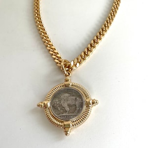Puede incluir: Un collar de cadena de oro con un colgante que presenta una moneda estadounidense vintage de cinco centavos con un dise&ntilde;o de b&uacute;falo. La moneda est&aacute; rodeada por un marco decorativo de oro.