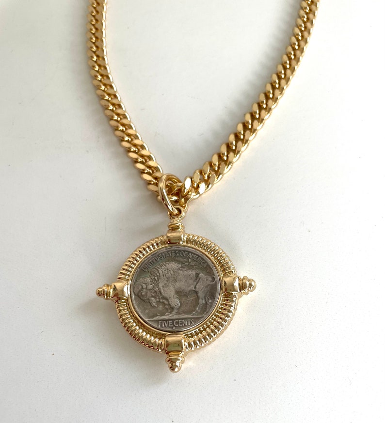 Puede incluir: Un collar de cadena de oro con un colgante que presenta una moneda estadounidense vintage de cinco centavos con un dise&ntilde;o de b&uacute;falo. La moneda est&aacute; rodeada por un marco decorativo de oro.