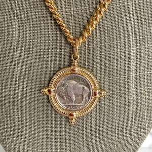 Puede incluir: Collar de cadena de oro con un colgante que presenta una moneda estadounidense vintage de cinco centavos con un dise&ntilde;o de b&uacute;falo. La moneda est&aacute; rodeada de un marco dorado con acentos decorativos.