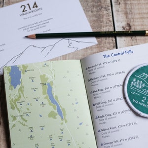 K&ouml;nnte beinhalten: Ein gr&uuml;ner und wei&szlig;er Aufn&auml;her mit dem Text "214 Wainwrights" und einer Illustration einer Bergkette. Der Aufn&auml;her befindet sich auf einer Seite mit einer Liste von Bergen und deren H&ouml;hen in Metern und Fu&szlig;. Die Seite ist auf den Abschnitt mit dem Titel "The Central Fells" ge&ouml;ffnet.