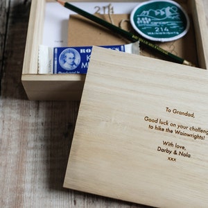 K&ouml;nnte beinhalten: Eine Holzkiste mit einer handgeschriebenen Nachricht im Inneren. Die Nachricht lautet: "To Grandad, Good luck on your challenge to hike the Wainwrights! With love, Darby & Nola xxx".