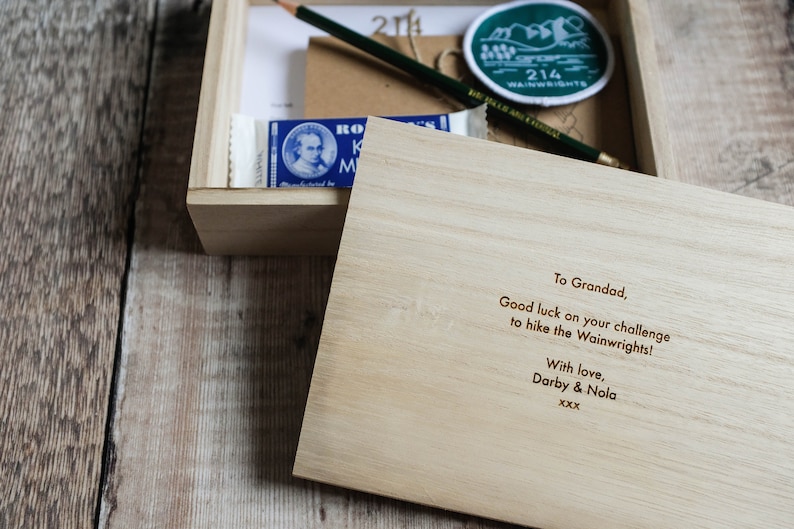 K&ouml;nnte beinhalten: Eine Holzkiste mit einer handgeschriebenen Nachricht im Inneren. Die Nachricht lautet: "To Grandad, Good luck on your challenge to hike the Wainwrights! With love, Darby & Nola xxx".
