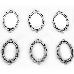May include: Six silver oval-shaped pendant trays with a decorative scalloped edge. The trays are designed to hold a flat-backed cabochon or other embellishment.