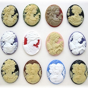 May include: Twelve oval-shaped cameo pendants with various designs featuring women and children. The cameos are set in different colored resin, including black, white, green, red, pink, blue, and brown.
