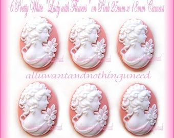 May include: Six white cameo-style buttons with a lady with flowers design on a pink background. Each button is 25mm x 18mm.