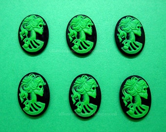 May include: Six green and black cameo-style buttons with a skull and bones design. The buttons are oval shaped and have a raised design.
