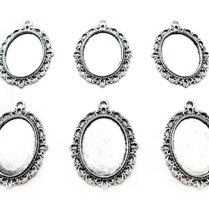 May include: Six silver oval-shaped pendant trays with ornate filigree designs. The trays are blank and ready for crafting.