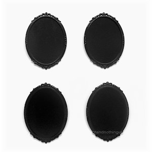 May include: Four black oval-shaped frames with ornate detailing. The frames are blank and have a matte finish.