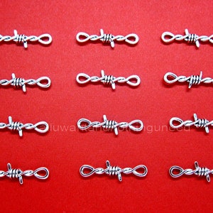 May include: Silver-colored barbed wire charms arranged on a red background. Each charm features a detailed barbed wire design between two looped ends. The charms are evenly spaced, creating a visually appealing pattern.