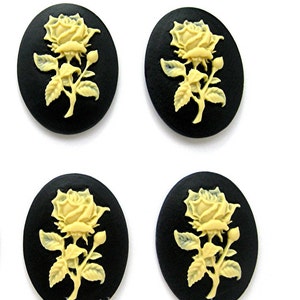 May include: Four black oval-shaped cameos with a raised white rose design. The cameos are perfect for crafting projects.