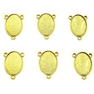 May include: Six gold-toned oval-shaped metal frames with three loops on each frame. The frames are designed to hold a cameo or other decorative element.