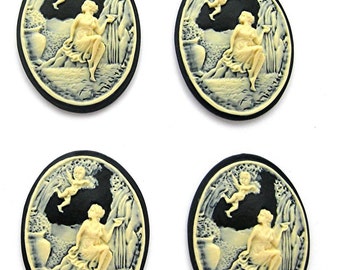 May include: Four black and white cameo-style buttons with a raised design of a woman sitting in a garden with a cherub flying above her. The buttons are oval shaped and have a black background with a white design.